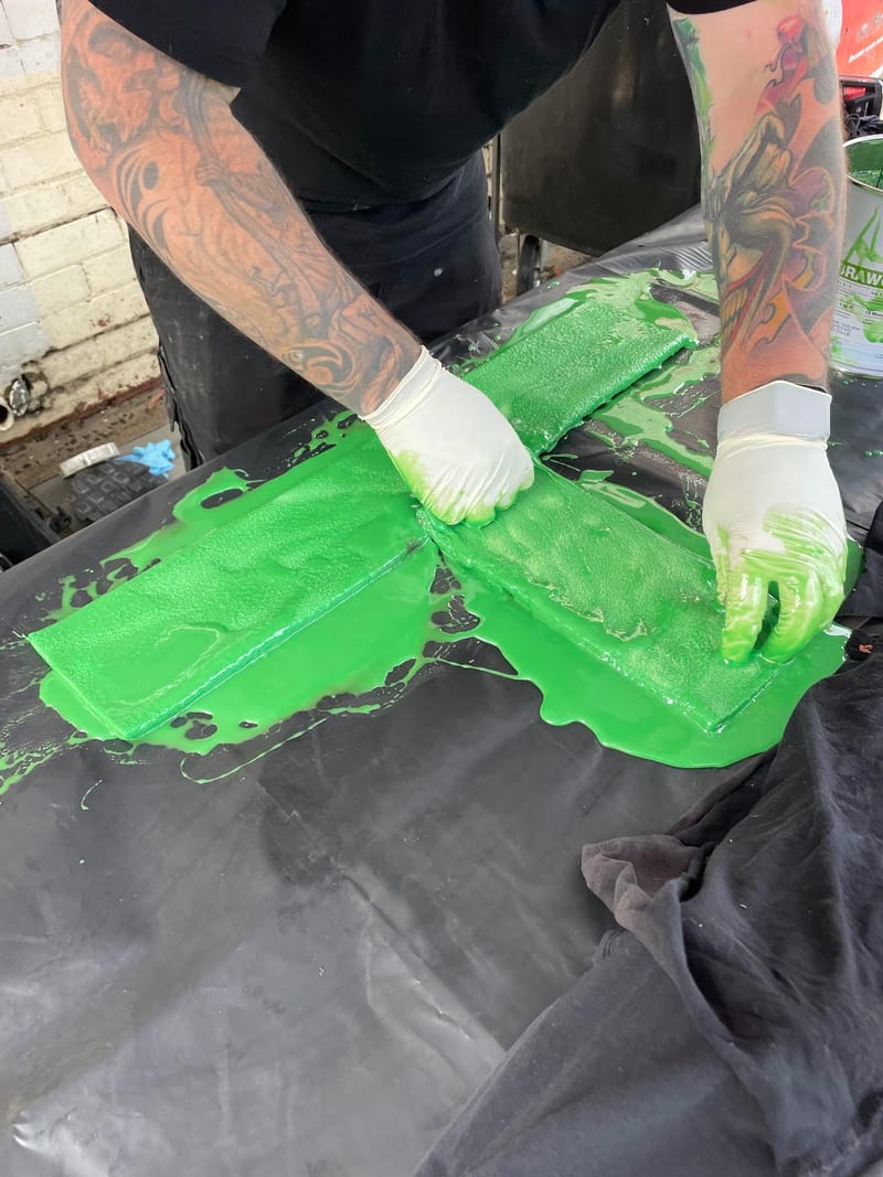 Drainpro plumber rolling green epoxy resin into the pipe liner before insertion